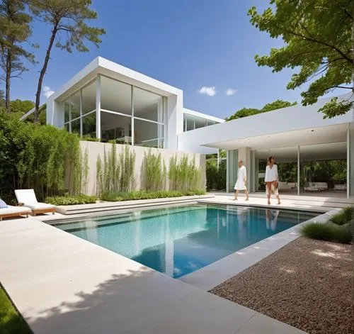 DISEÑO ESTERIOR DEL ACCESO A UNA RESIDENCIA, CON UN PORTON METALICO EN INMITACIÓN MADERA, CON PLANTAS DE FORMIO EN EL ACCESO, ARBOLES Y VEGETACIÓN EXUBERANTE,two women in white walking toward an outdo