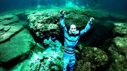 the man in blue scubasuit is standing on the rocks,blue cave,wachee,the blue caves,freediving,blue caves,cenotes