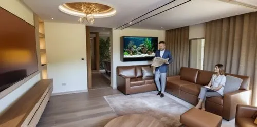 luxury fish tank with decoration, lights and a variety of fishes. the tank is flush with the wall and over looks the dining area on the backside,a lady in blue standing next to some couches,modern roo