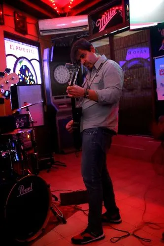 a man standing on the floor looking at a cell phone,clawhammer,sitarist,live music,guitar player,soloing,banjo player