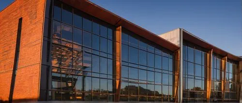 Modern UIUC architecture, sleek glass exterior, metallic frames, geometric shapes, futuristic design, urban cityscape, dusk time, warm orange lighting, soft shadows, reflective windows, intricate deta