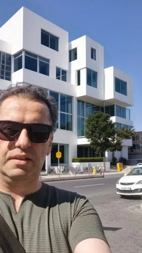 modern white architecture, inspired by richard meier architecture style,  ,man in shades holding onto a camera outside a large white building,googleplex,technion,sunnyvale,ufrj,ucsf,moscone