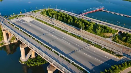 a road bridge over the river with two lines for trams in the center of the bridge. From the bridge you can see a beautiful view of the Tom River in Kuzbass. The bridge itself is decorated with lamppos