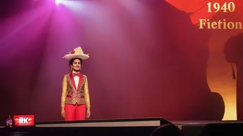 Veer Kamal conducting a magic show on stage. Renuka Chouhan as Amrita Kumaran watching from the seat,prithvi,tricentenary,prithviraj,great as a stilt performer,bicentenary,mahotsav,pietton,telethon,th