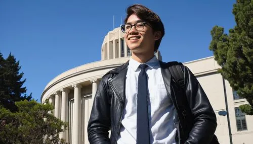 UC Berkeley architecture graduate, male, 25yo, bespectacled, short brown hair, casual smile, black leather jacket, white shirt, dark blue jeans, sneakers, backpack, holding a rolled-up blueprint, stan