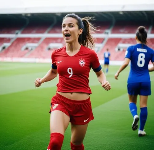 Same person wearing soccer cleats, soccer socks, soccer pants bra. she has abs. She scored a goal on a soccer pitch and celebrating by holding her red soccer jersey in her hand. she is running up the 