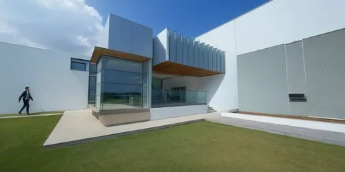 a person walking in a grass field near two buildings,cube house,cubic house,modern architecture,modern house,maxxi,cube stilt houses,Photography,General,Realistic