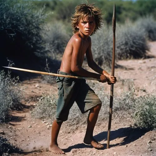 Shirtless sunburn barefoot filthy dirty angry young boy in the wild holding a spear with messy hair covered in sweat dirt and scars in bright sunshine in blazing heatwave sneaking around hunting in th