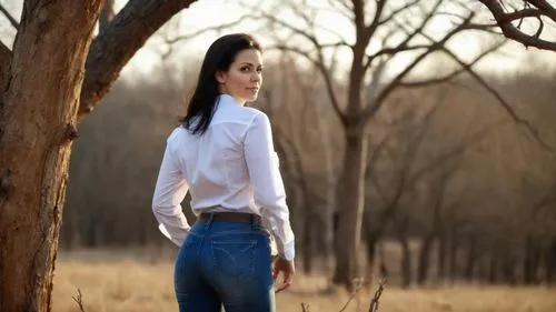 The beautiful 50-year-old woman with very long brown hair looks sadly at the dry tree, her face is extremely beautiful and calm, her lips are sensual, she expresses sadness on her face, the breeze gen