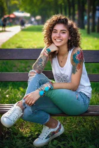 Free spirit, young woman, 20yo, messy curly brown hair, bright smile, colorful tattoo sleeve, casual ripped jeans, white tank top, sneakers, relaxed pose, sitting cross-legged, park bench, sunny after