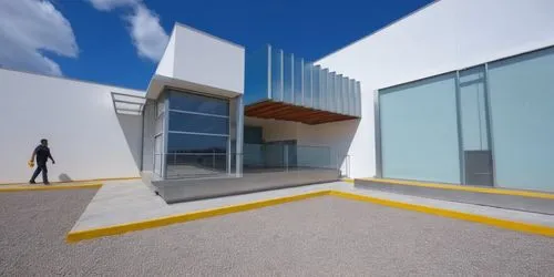 AREA DE CONVIVENCIA, CON PERGOLAS DE CONCRETO, LOSA CON REMATE DE VIGA DE ACERO, ESPEJO DE AGUA ,a man with a luggage bag is walking in front of a large glass building,cubic house,cube house,3d render