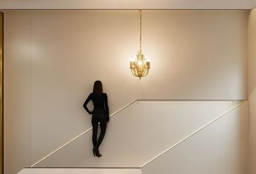 a powder room, with a gold chandelier in the middle of the room, a young woman in the middle of the powder room,a woman in black posing in a stairwell with light bulbs,wall light,foscarini,sconces,ass