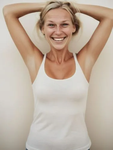 a very happy looking Swedish woman holds her head,a woman with long blonde hair and wearing a white tank top smiling,mirifica,procollagen,noninvasive,liposuction,premenopausal,microdermabrasion