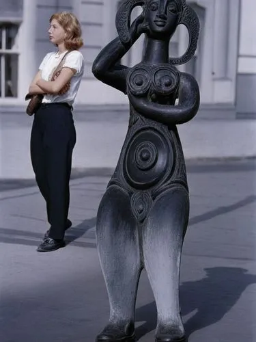 Two different women.,a woman standing by a tall sculpture on the side of the road,paolozzi,woman sculpture,sculptors,sculptor ed elliott,png sculpture,staudacher,Photography,Black and white photograph