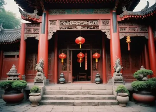 Traditional Chinese vernacular architecture, ancient temple, intricately carved wooden doors, vibrant red walls, upturned eaves, golden roof tiles, ornate ceramic decorations, lanterns hanging from th