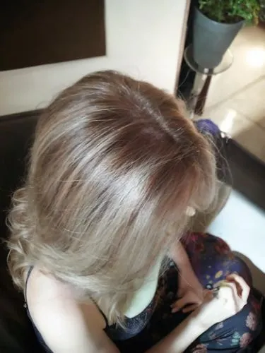 the view is from above the woman is sitting sideways and has long hair, keep her hands the same,chignon,blond hair,short blond hair,blonde sits and reads the newspaper,blonde on the chair,hair colorin