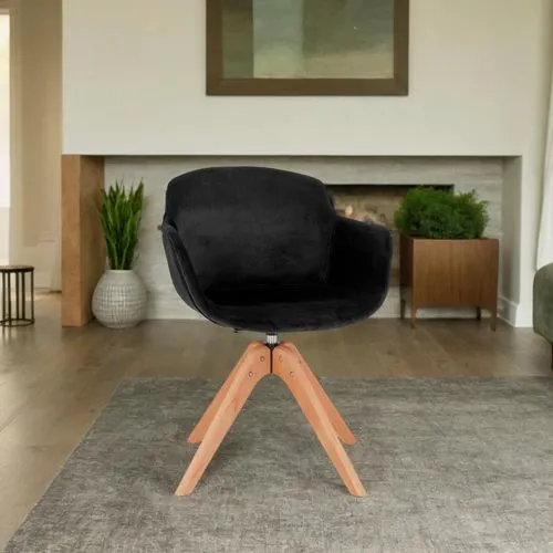 A modern Scandinavian living room with a welcoming, lived-in feel, featuring a sleek black velvet chair as a key element. The room is bathed in natural light pouring through expansive, floor-to-ceilin