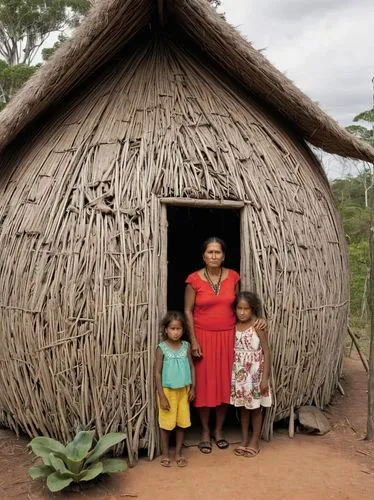 45-year-old Aboriginal woman in front of a native hut with her daughter, who was fathered by a German 15 years ago.,an elderly woman and two young children standing outside of their home made out of s