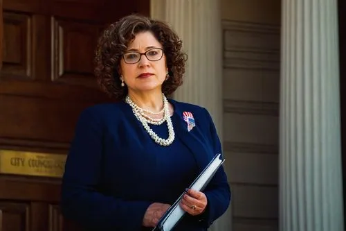 Washington D.C. city council building, grand architecture, columns, dome roof, American flag waving, mature lady politician, formal wear, pearl necklace, curly brown hair, glasses, confident posture, 