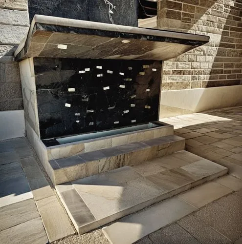 antique fountain.blasted stone.marble covering.marble motif.decorative marble elements.shaped marble pieces.,some steps going up to a small black box,holocaust memorial,columbaria,columbarium,wine rac