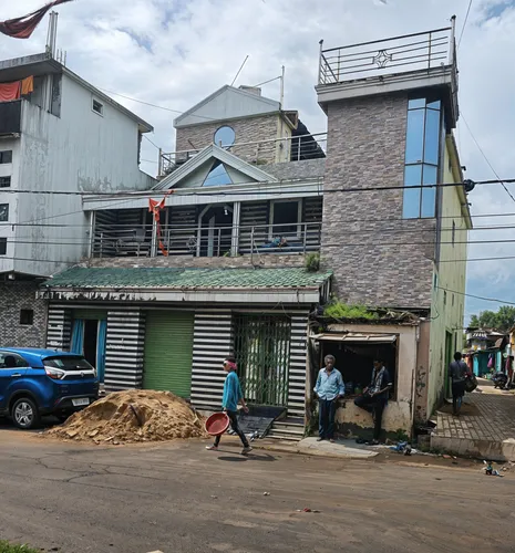 a blue truck driving past a building with people in it,monrovia,rongai,trenchtown,koforidua,douala,hammermill