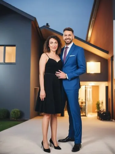 Mr. and Mrs. Maurer in front of their German single-family home bungalow in the city.,a young man and woman standing in front of a house,homebuyers,social,homeowners,home ownership,house sales,estate 