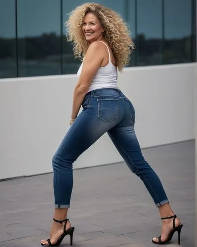 side view of a beautiful verry curvy 50yo radiantingly german woman long and curlyfro blonde hair,  smile, big round butt, fit body, spaghetti top, denim jeans righteous, summer sandals with plattform