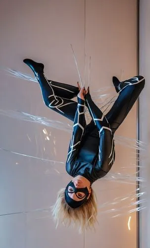 a photography of a beautiful caucasian blonde girl 22 years old, she is wearing a black mask and a black and white suit of spider woman of Marvel, she is head stop holding whit your hands some cables 