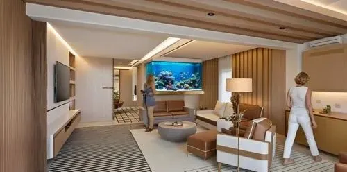 fish tank with coral reef and many fishes,the person stands in front of a large screen tv,luxury bathroom,stateroom,modern room,staterooms,hotel hall,luxury hotel