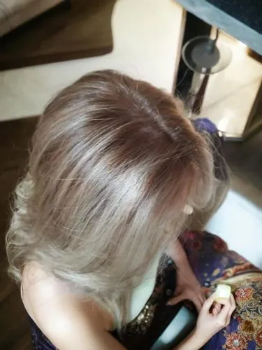 the view is from above the woman is sitting sideways and has long hair, keep her hands the same,hairdressing,hair coloring,chignon,hairstylist,hairdressers,blond girl,hair dresser,hairdresser,blonde o