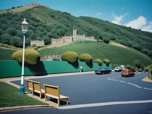 Eine Zeichnung von Bill Denny in sattem Grasgrün: Die Skyline der Malvern Hills bei Great Malvern leuchtet hell gegen den blauen Himmel darüber. Die Gebäude sind eine bunte Mischung aus tiefen Grautön