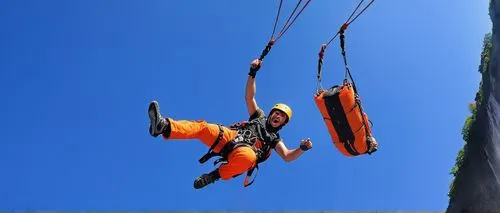 Thrilling bungee jumping scene, Niagara Falls background, daytime, sunny weather, clear blue sky, majestic waterfall mist, adventurous young adult, helmet, harness, safety rope, bright orange jumpsuit