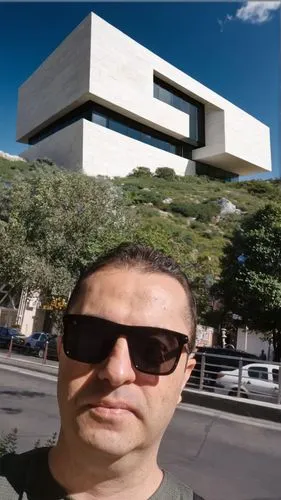 modern cubic white stone building,a man with sunglasses on a street next to trees,macba,niemeyer,maxxi,ufmg,guggenheim museum,ufrj