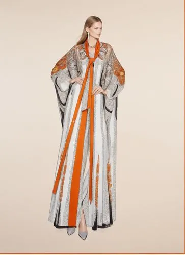 a woman standing in front of a white background,imperial coat,etro,coat,housecoat,long coat,dreamcoat,Photography,Fashion Photography,Fashion Photography 04