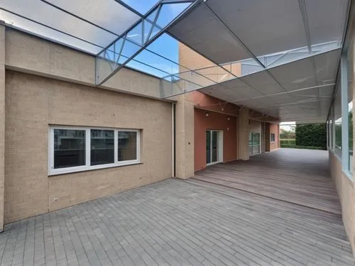 The wall is made of beige stone blocks, up to the windows, then the walls are covered with beige plaster. WINDOWS WITH white FRAMES and an entrance door, the roof is structurally COVERED WITH TRANSPAR