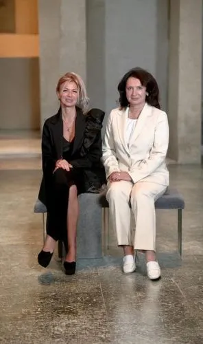 two women sitting on a bench in an empty room,chairwomen,headmistresses,abfab,cochairs,abramovic,pantsuits