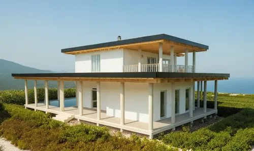 Small modern house surrounded by a cottage community.
The walls are white. Black roof.,the modern home is nestled at the side of a hill,lifeguard tower,observation tower,lookout tower,stilt house,watc