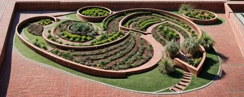 model seen from above of an organic
  public garden built in the desert with red bricks. In the circumference of the garden there are palm trees. there are bridges, stairs and ramps that connect the d