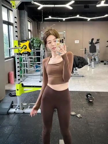 an asian woman standing up holding a cell phone,gym,hyosung,hyoseong,workout,gym girl,jungwirth