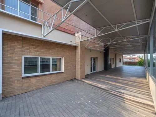 The wall is made of beige stone blocks, up to the windows, then the walls are covered with beige plaster. WINDOWS WITH white FRAMES and an entrance door, the roof is structurally COVERED WITH TRANSPAR