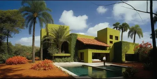 EL EXTERIOR DE UNA CASA CON ESTILO MEXCANO MODERNO, USO DE COLORES VIBRANTES, MATERIALES REFIONALES, TEJA, VIGAS DE MADERA, EN UN AMBIENTE EXUBERANTE, ESTANQUE DE AGUA AL FRENTE.,a person standing in 