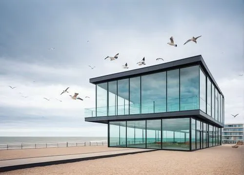 Lowestoft, Suffolk, UK, coastal town, architectural design, modern building, glass facade, steel structure, rectangular shape, flat roof, large windows, ocean view, beachside, seagulls flying, cloudy 