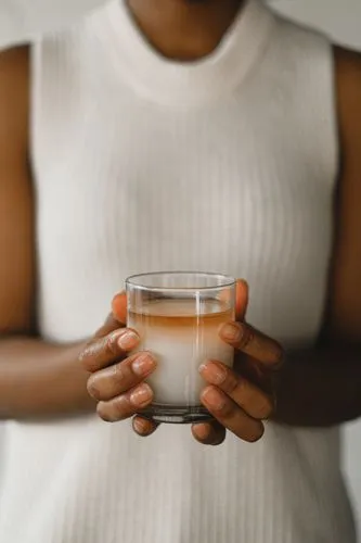 cortado,glass of milk,woman drinking coffee,a candle,tea candle,a cup of coffee