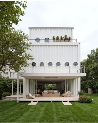 A photo shows a large white container bar with circular windows and an outdoor balcony extending to the entire front, serving as both a gathering space for crowds and an outdoor resting area. One side