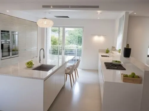 A kitchen design featuring only smooth, handleless cabinet fronts in pure white color. The cabinets have clean, modern lines, creating a minimalist and sleek aesthetic. The overall feel is one of orde