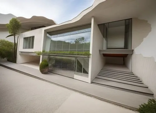 Diseño exterior de una residencia estilo mínimalista, con muros de concreto color blanco, perfiles con canal de acero en losa, ventanal de cristal en la parte superior del acceso, ventana en el estudi