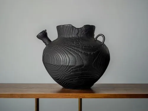 ваза стоит на деревянном столе  и на заднем фоне  белая стена ,a black vase is sitting on a table,vase,amphora,stoneware,earthenware,clay jug,copper vase