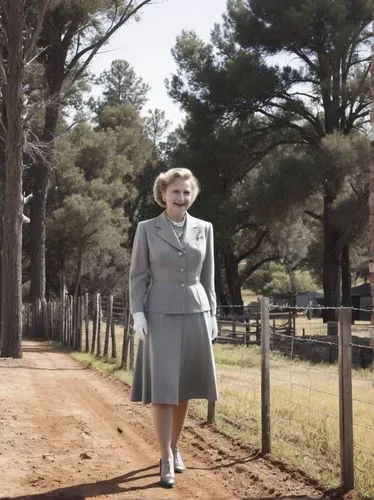 Eva Braun at the high fence on the border between Texas and Mexico.,a woman standing on top of a dirt road,blandings,queenie,woman walking,koningin,stateswoman,elizabeth ii,Photography,Black and white