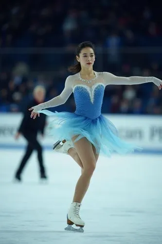 The image captures a halfbody closeup photo of figure skater in action on an ice rink. The focus is squarely placed on the female athlete, who appears to be performing during her routine with grace an