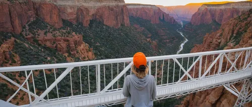 Woman in orange hat looking at a white bridge over a canyon thinking about her purpose as a caregiver in Englewood CO. We help caregivers process their grief and manage their stress in therapy at Cata